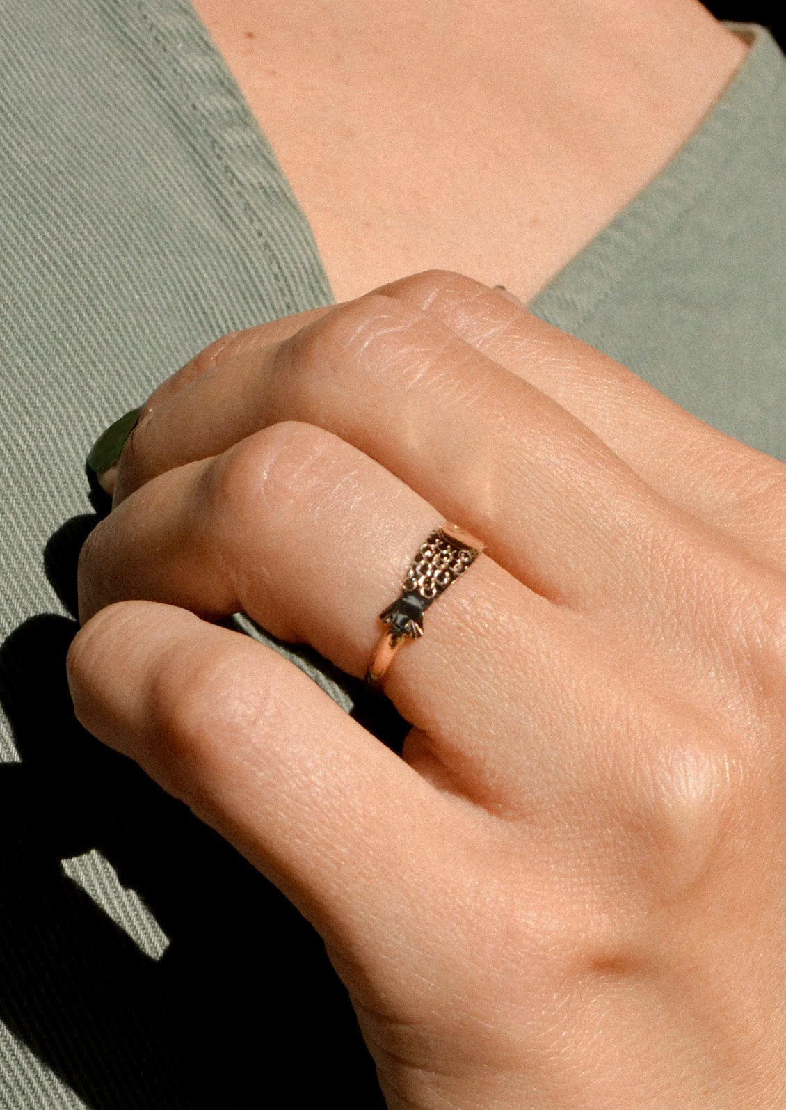 A woman wearing a gold ring in the shape of a sardine.