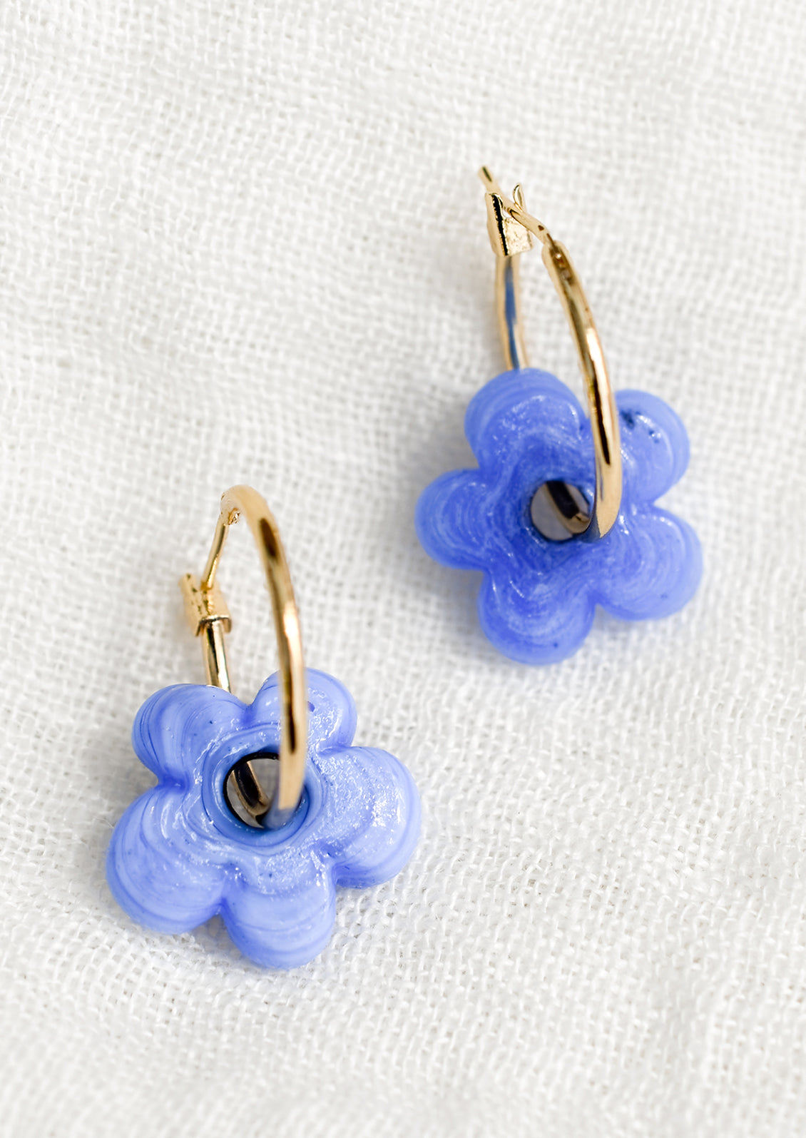 A pair of gold hoop earrings with single periwinkle flower bead.