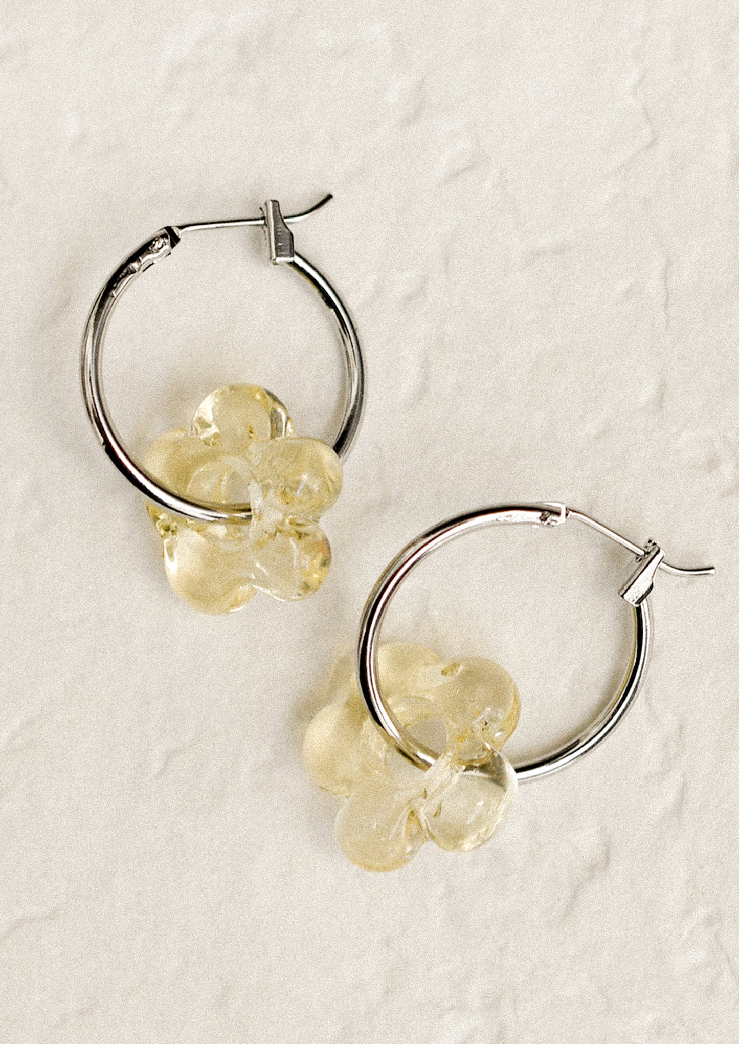 A pair of silver hoop earrings with floral Murano glass accents, displayed against a white background.