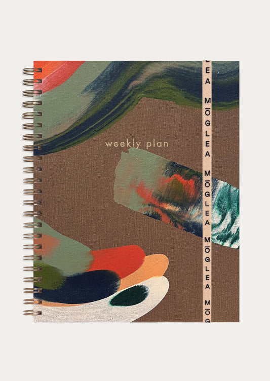 A hand painted wire bound planner reading "Weekly plan" on cover.