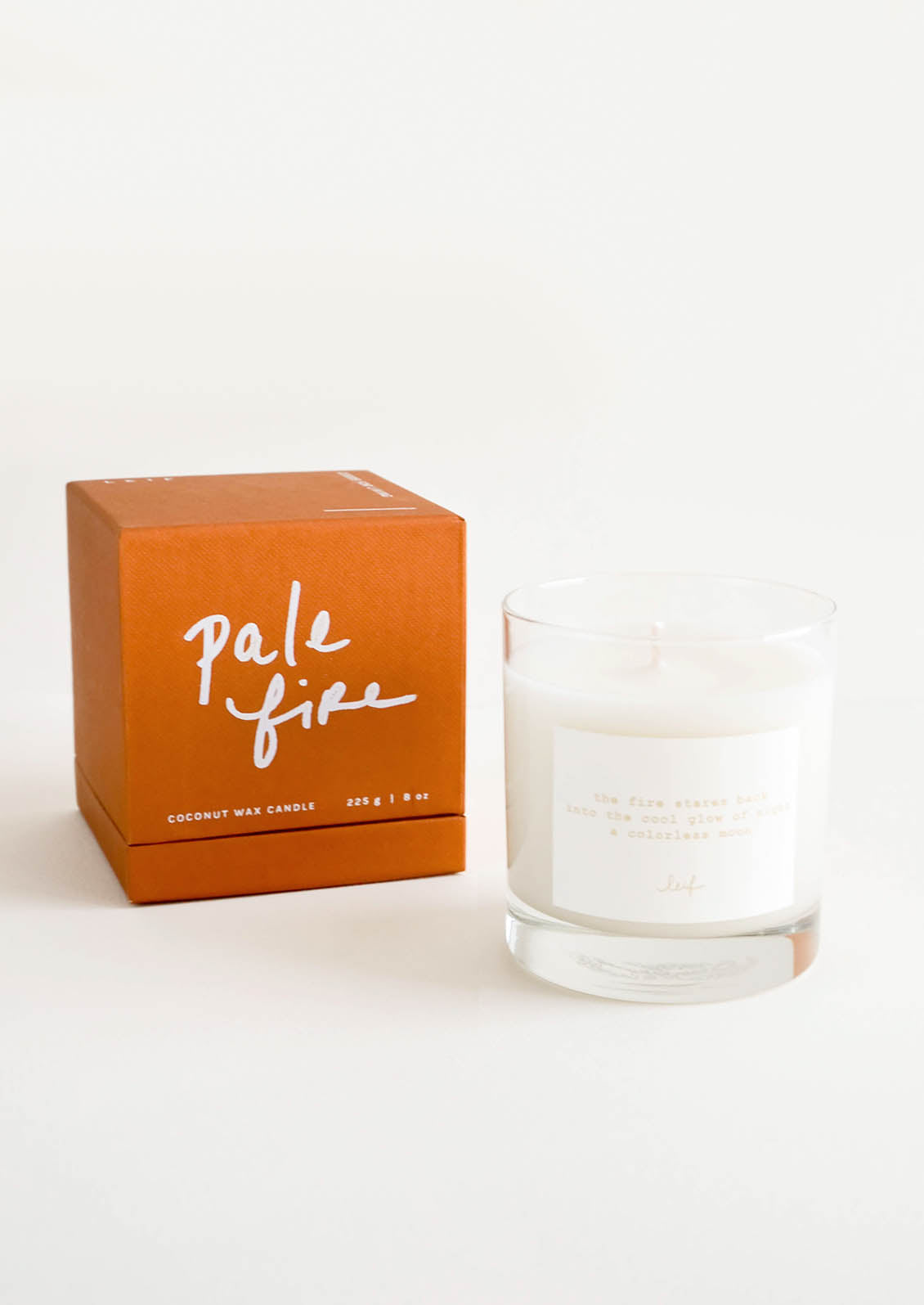 A glass candle with a white label sits next to a peach colored box reading "lost letters" in black cursive text.