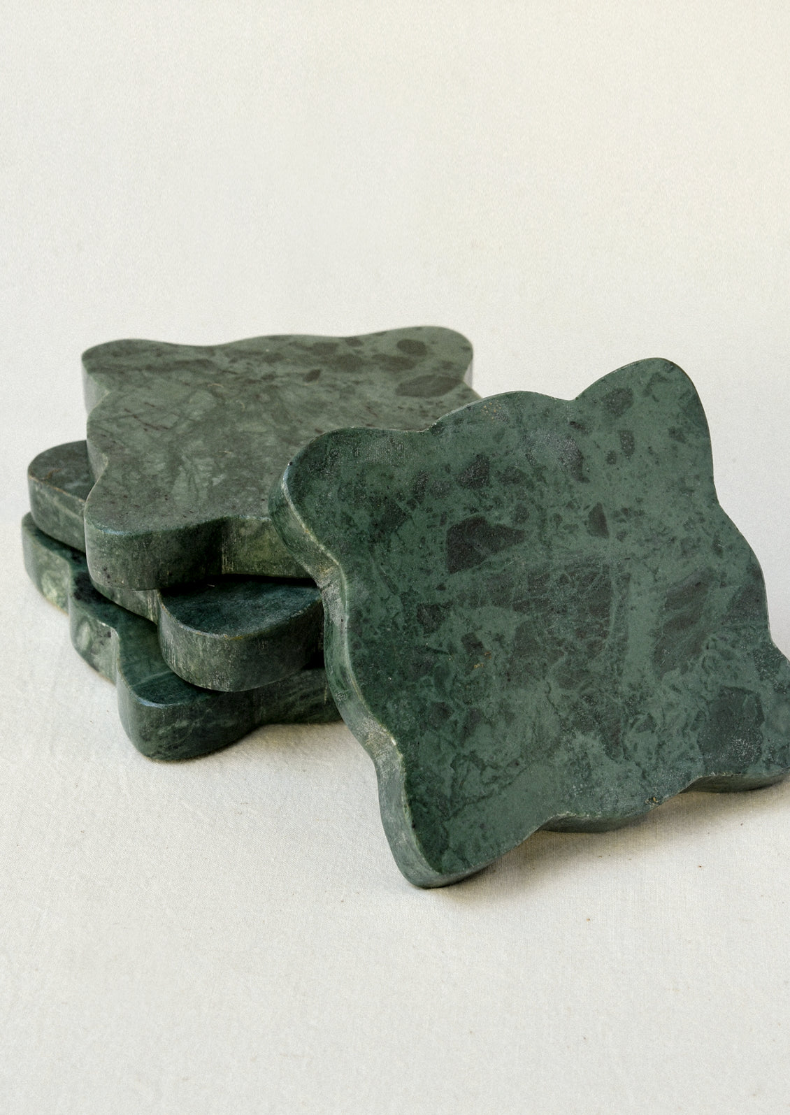 A set of 4 green marble coasters with scalloped edges.