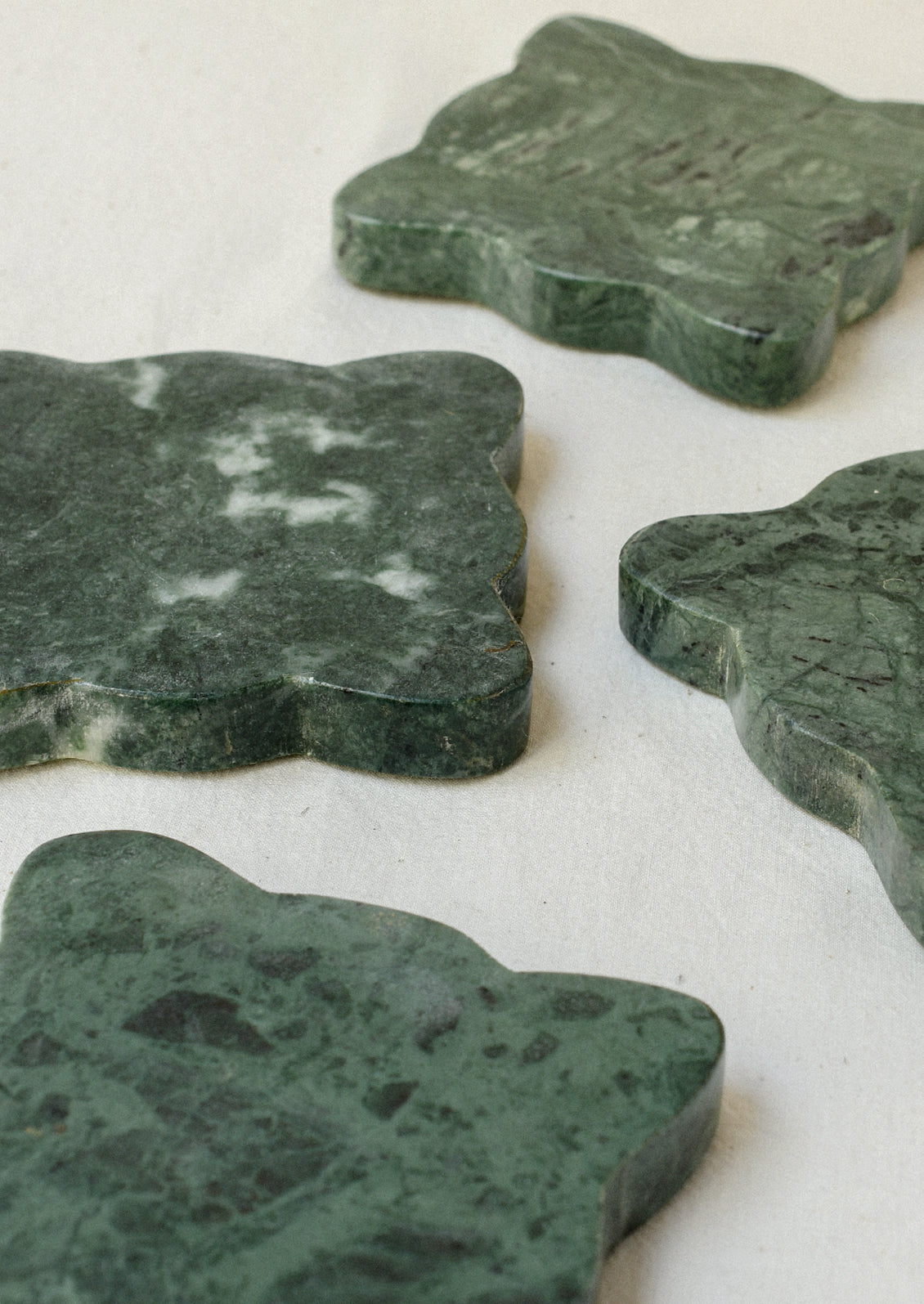 A set of 4 green marble coasters with scalloped edges.