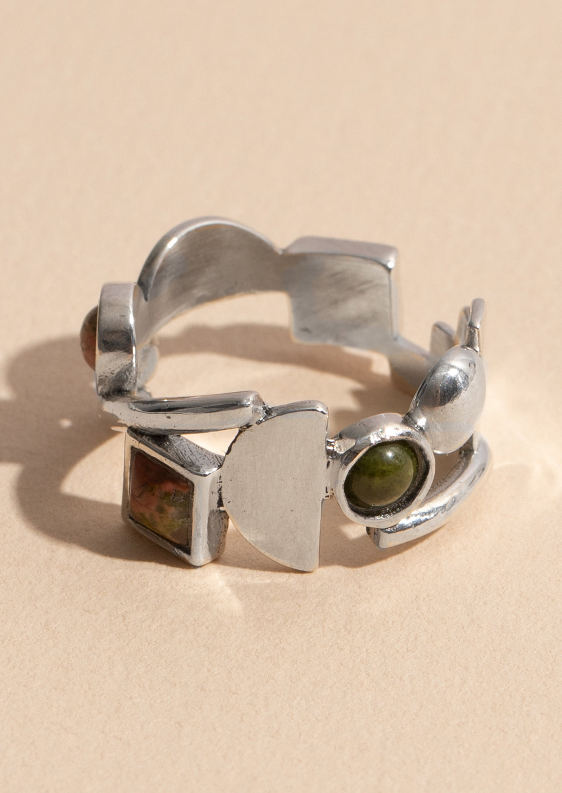 A silver ring with different geometric shapes among unakite gemstones.