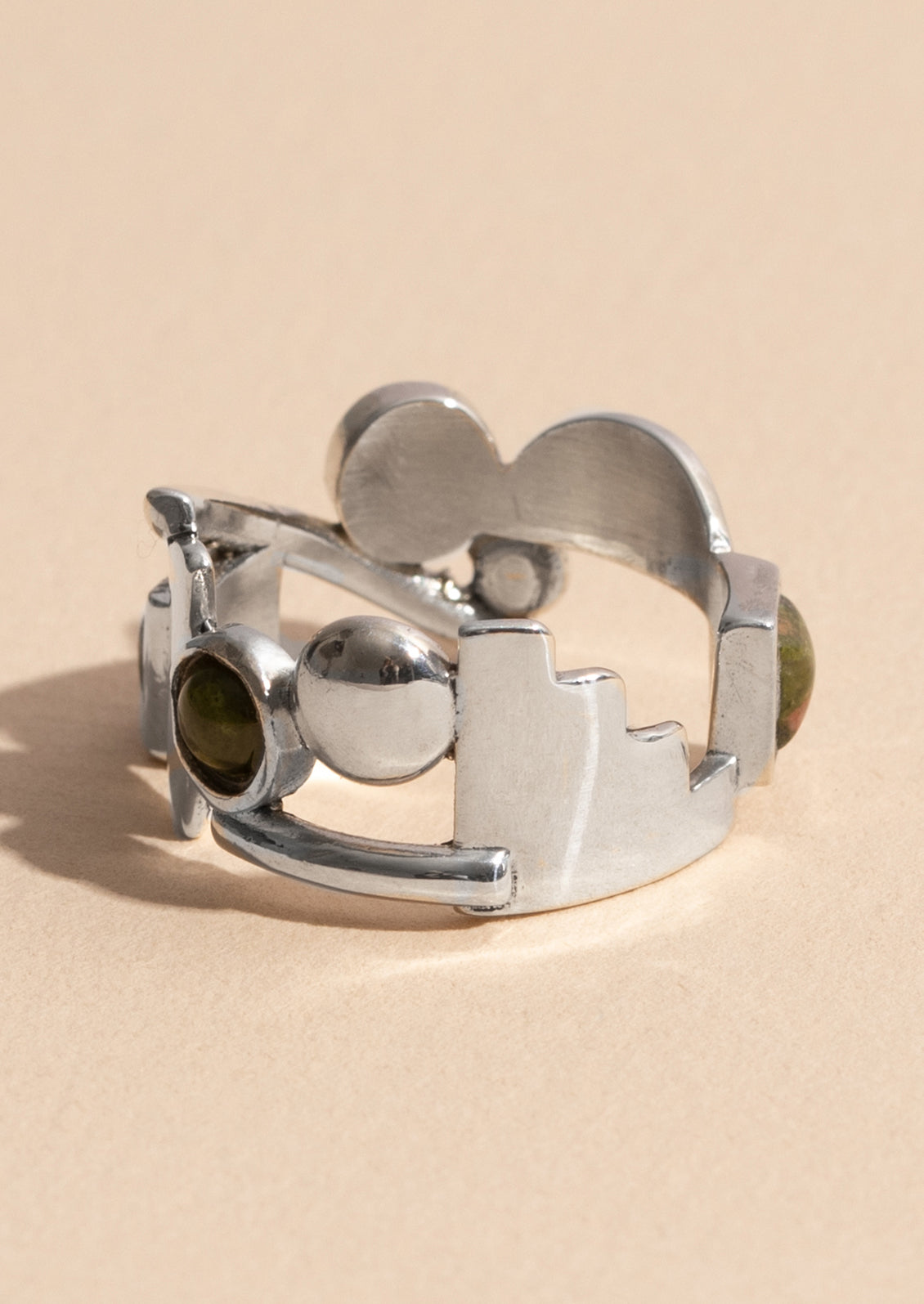 A silver ring with different geometric shapes among unakite gemstones.