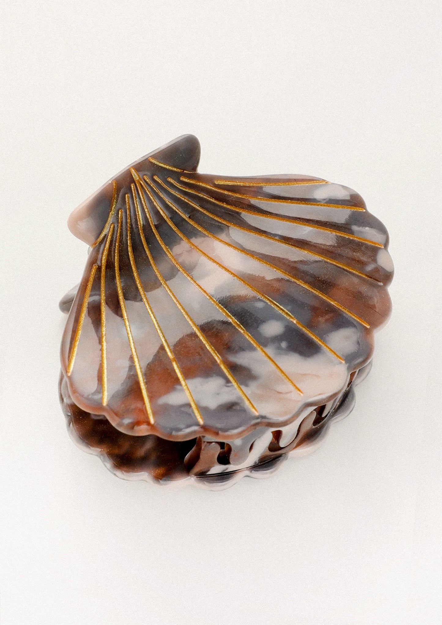 Shell-shaped hair clip with gold accents on a white background