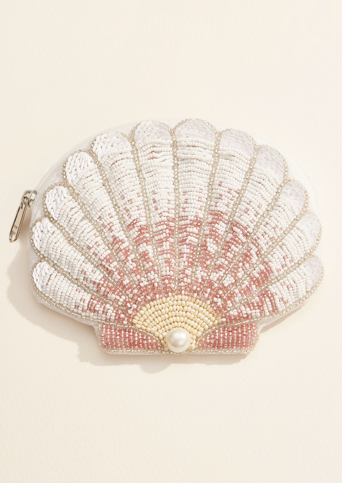 Shell-shaped pouch with beading and a pearl on a beige background