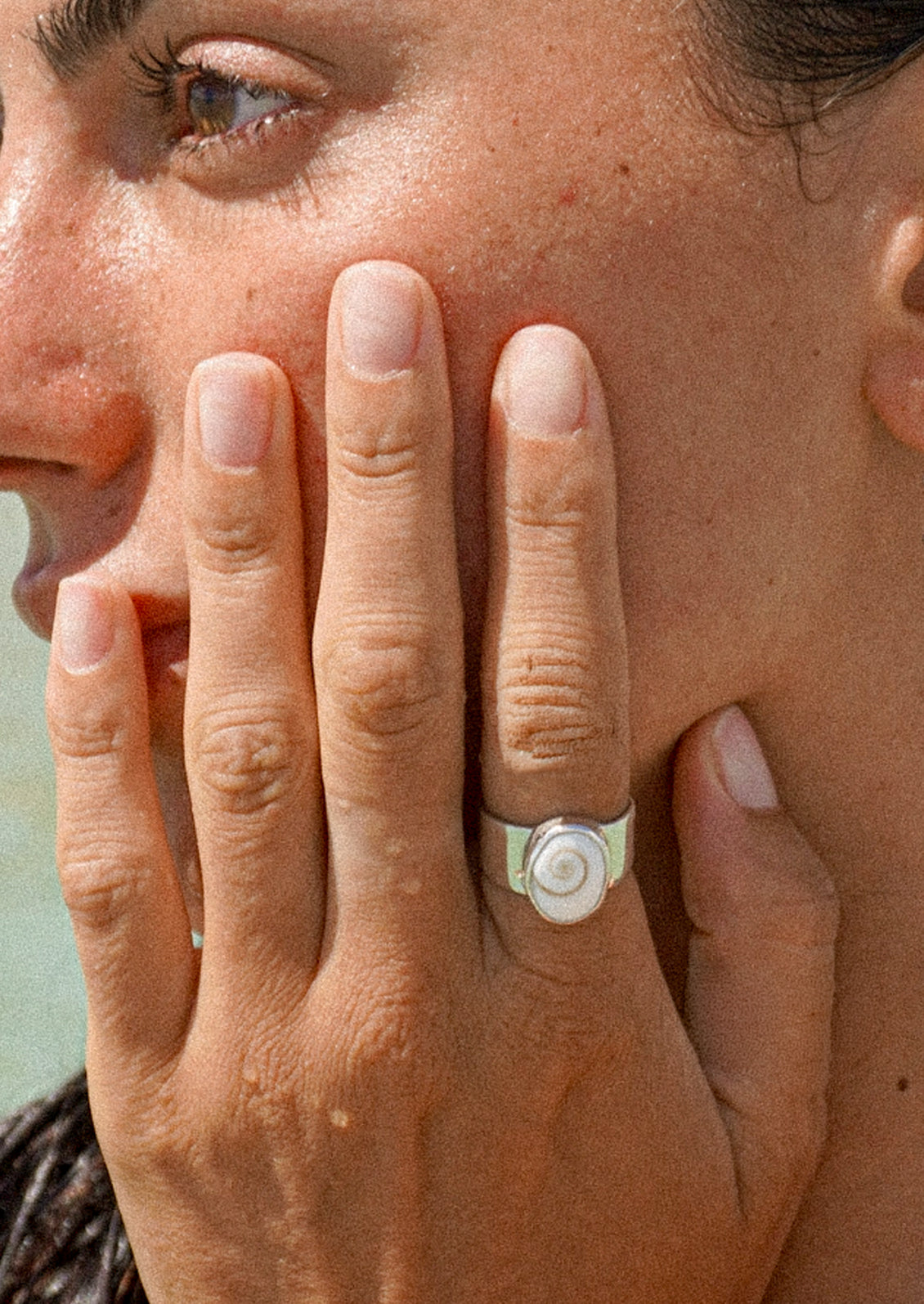 A woman wearing a thick silver ring with a shell signet.