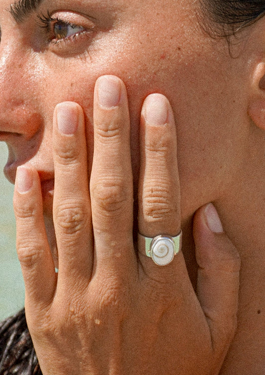 A woman wearing a thick silver ring with a shell signet.