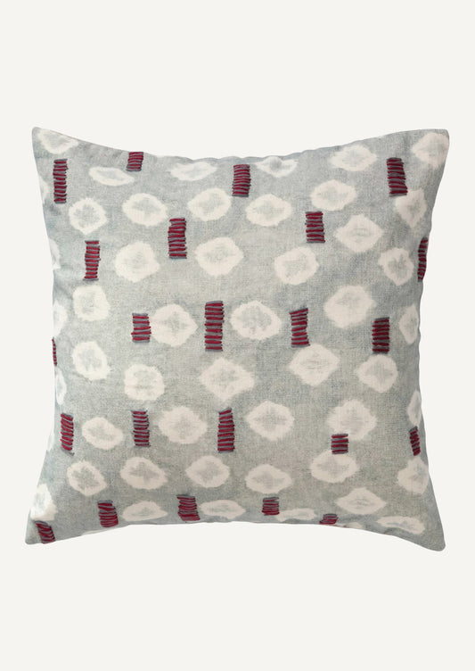 A square pillow in light blue batik tie dye pattern with red and grey embroidery detailing.