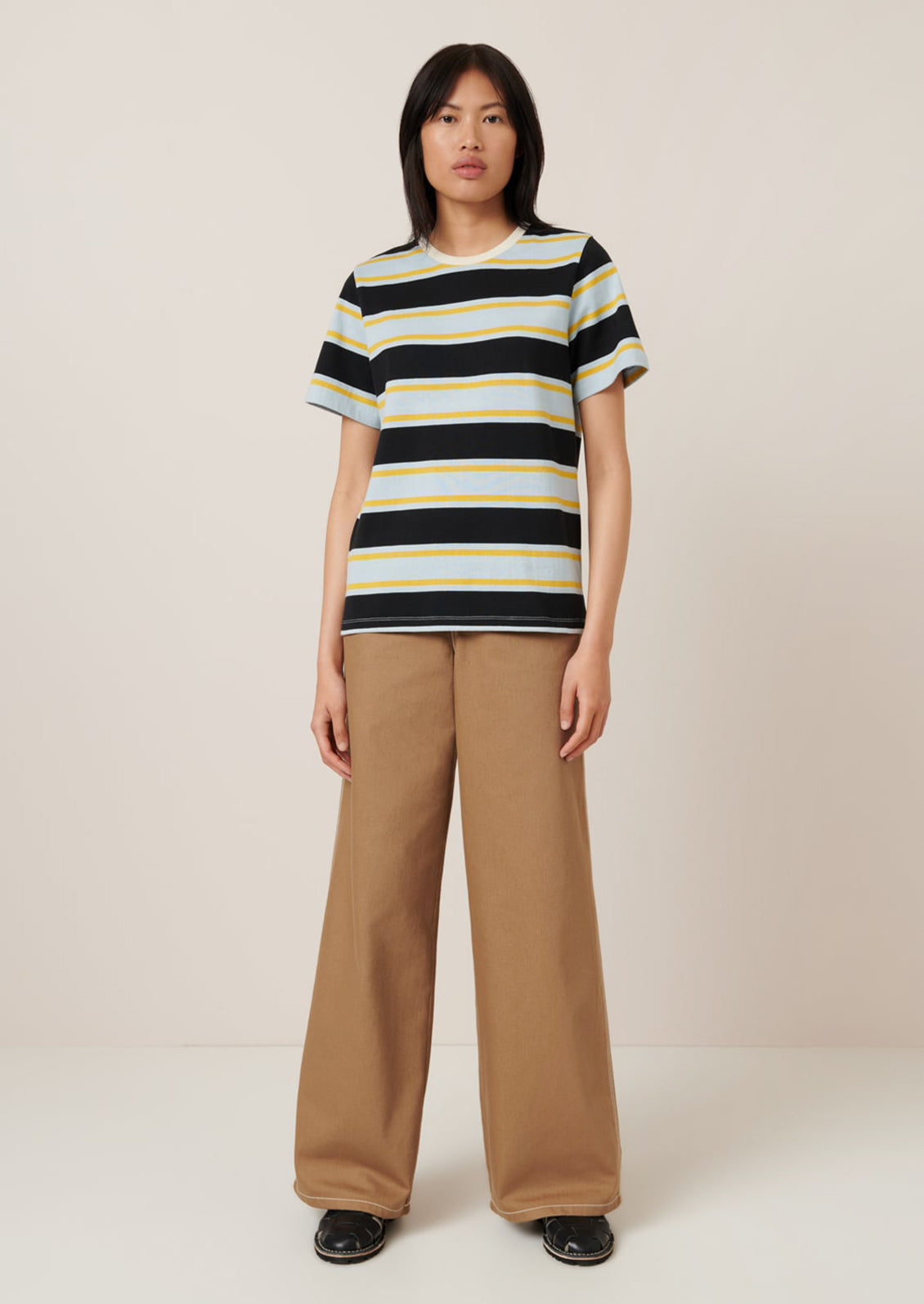 A person wearing a t-shirt with light blue, black and yellow rugby stripe pattern.