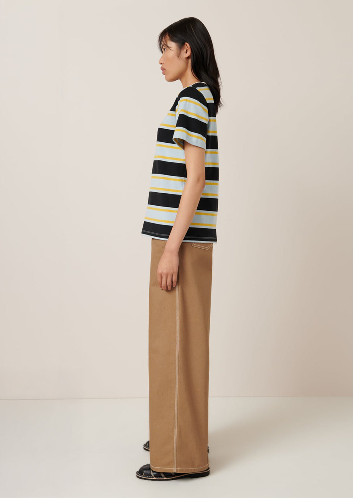 A person wearing a t-shirt with light blue, black and yellow rugby stripe pattern.