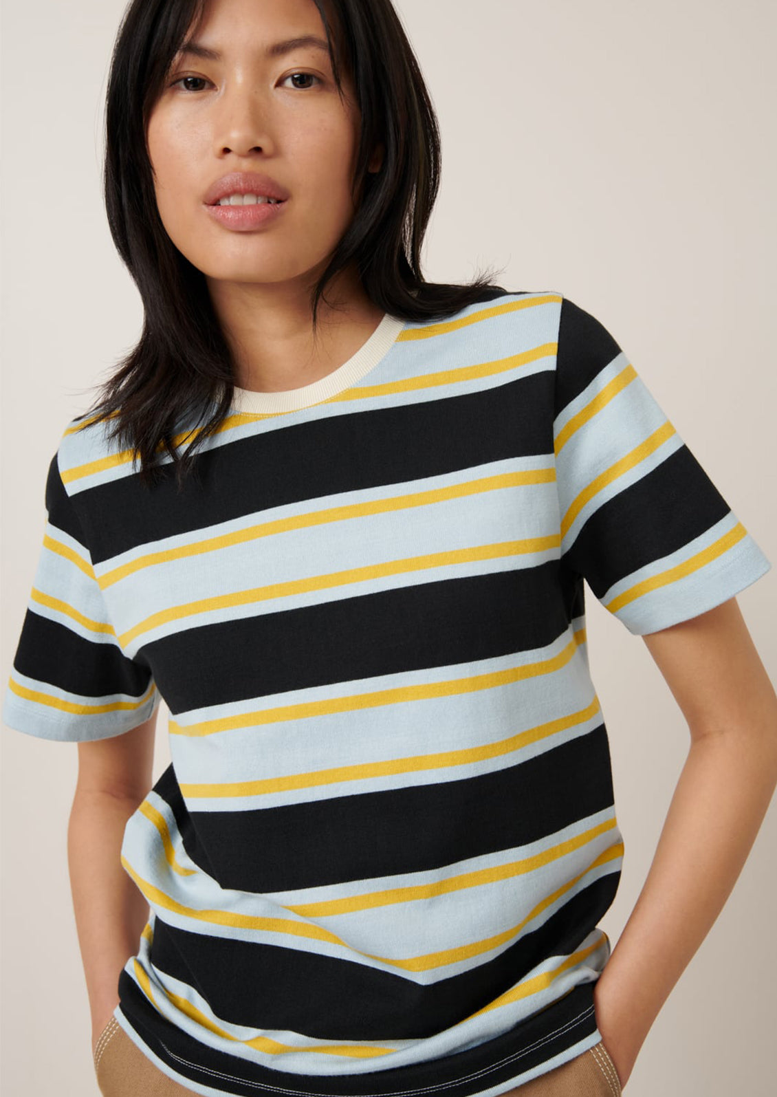 A person wearing a t-shirt with light blue, black and yellow rugby stripe pattern.