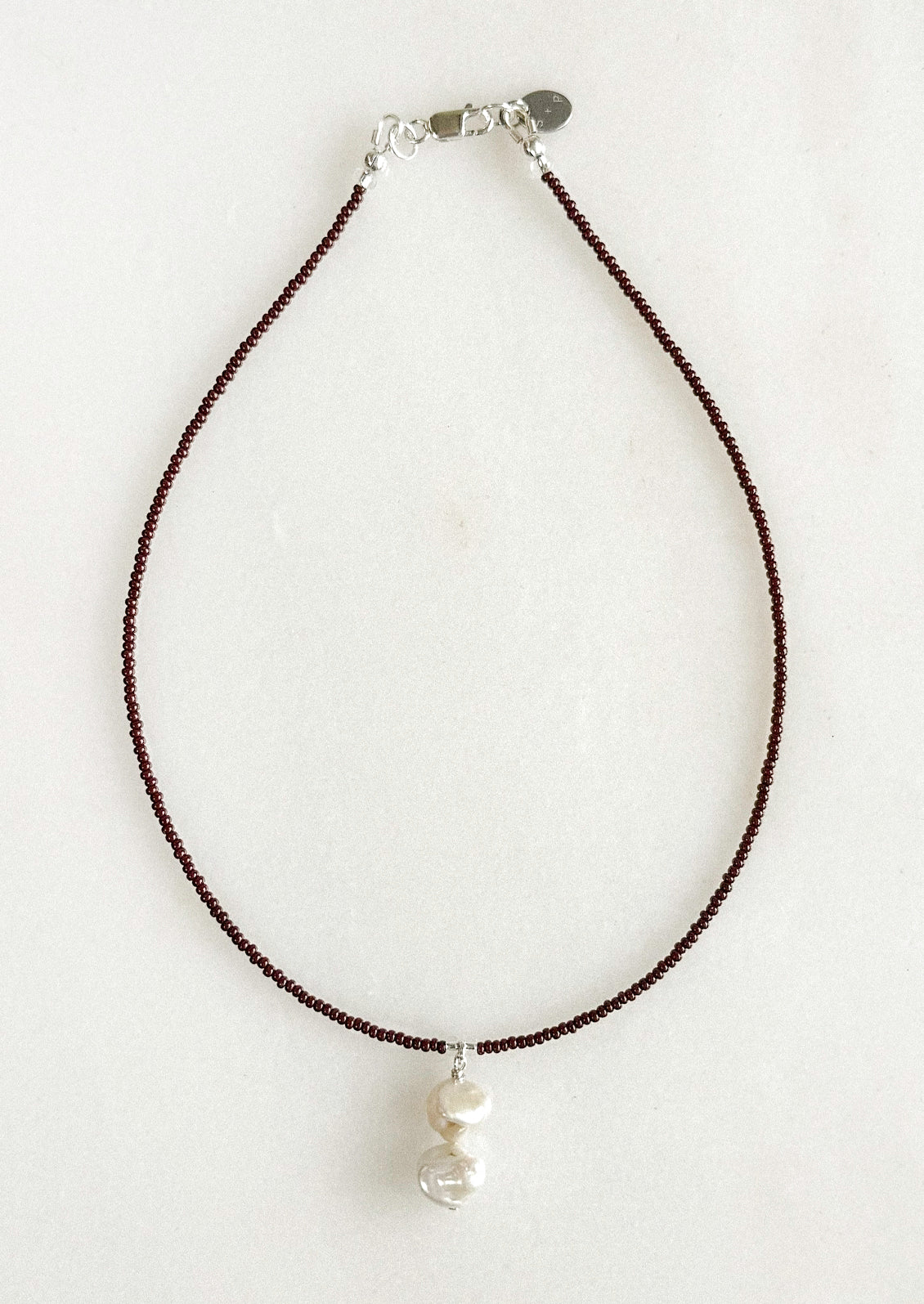 A necklace with small brown beads and a dangling freshwater pearl pendant.