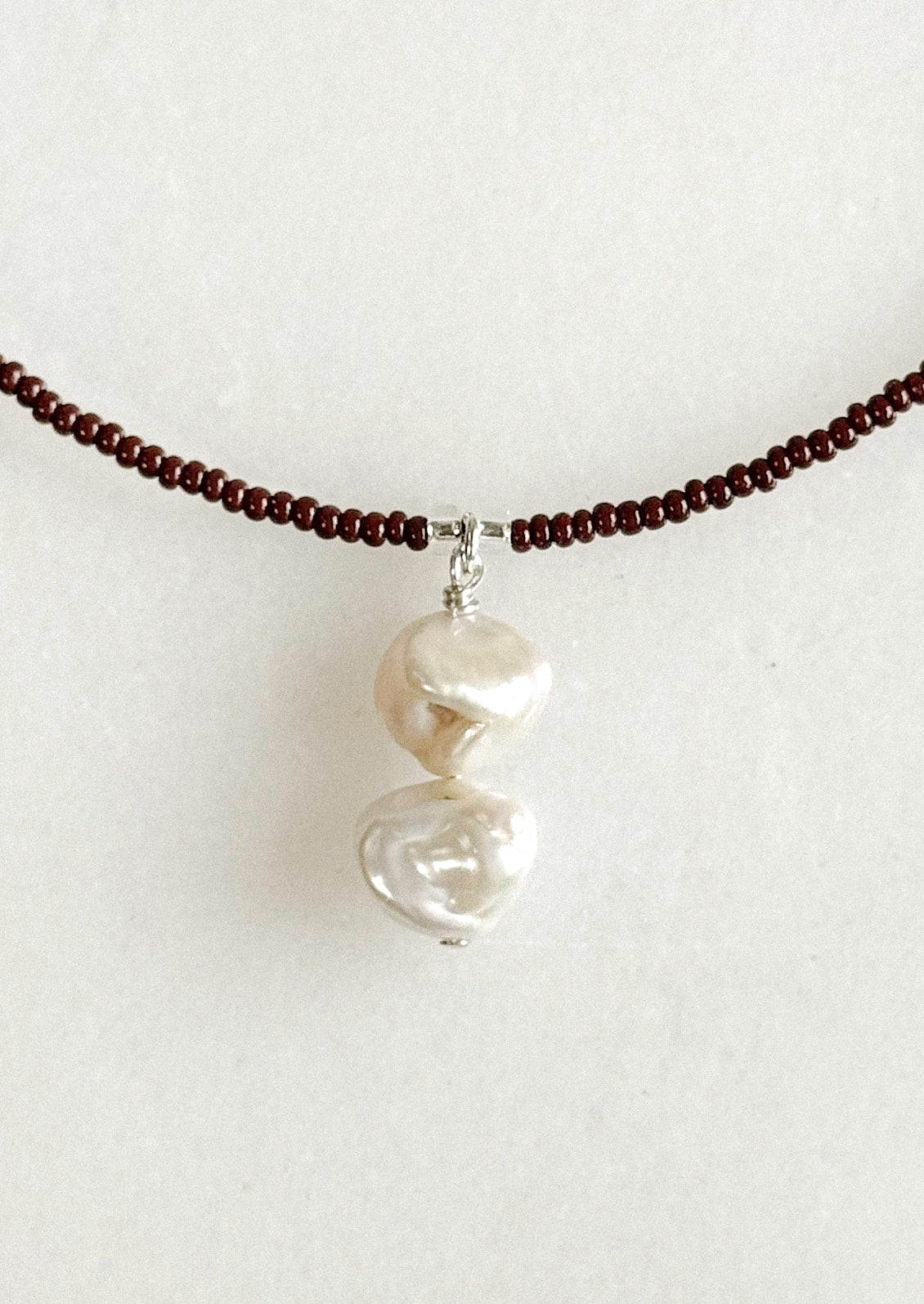 A necklace with small brown beads and a dangling freshwater pearl pendant.