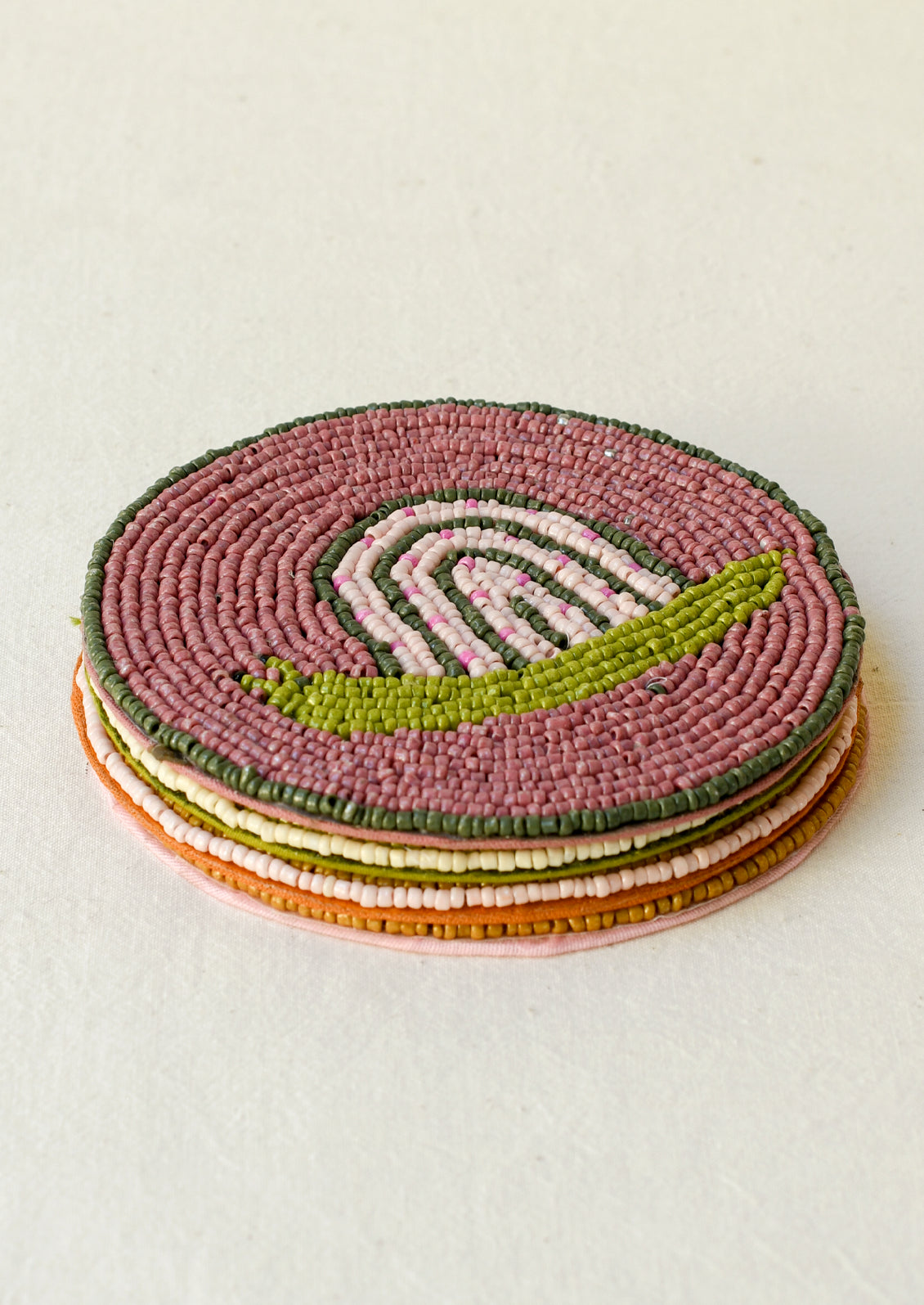 A stack of 4 beaded coasters with a different snail design on each.