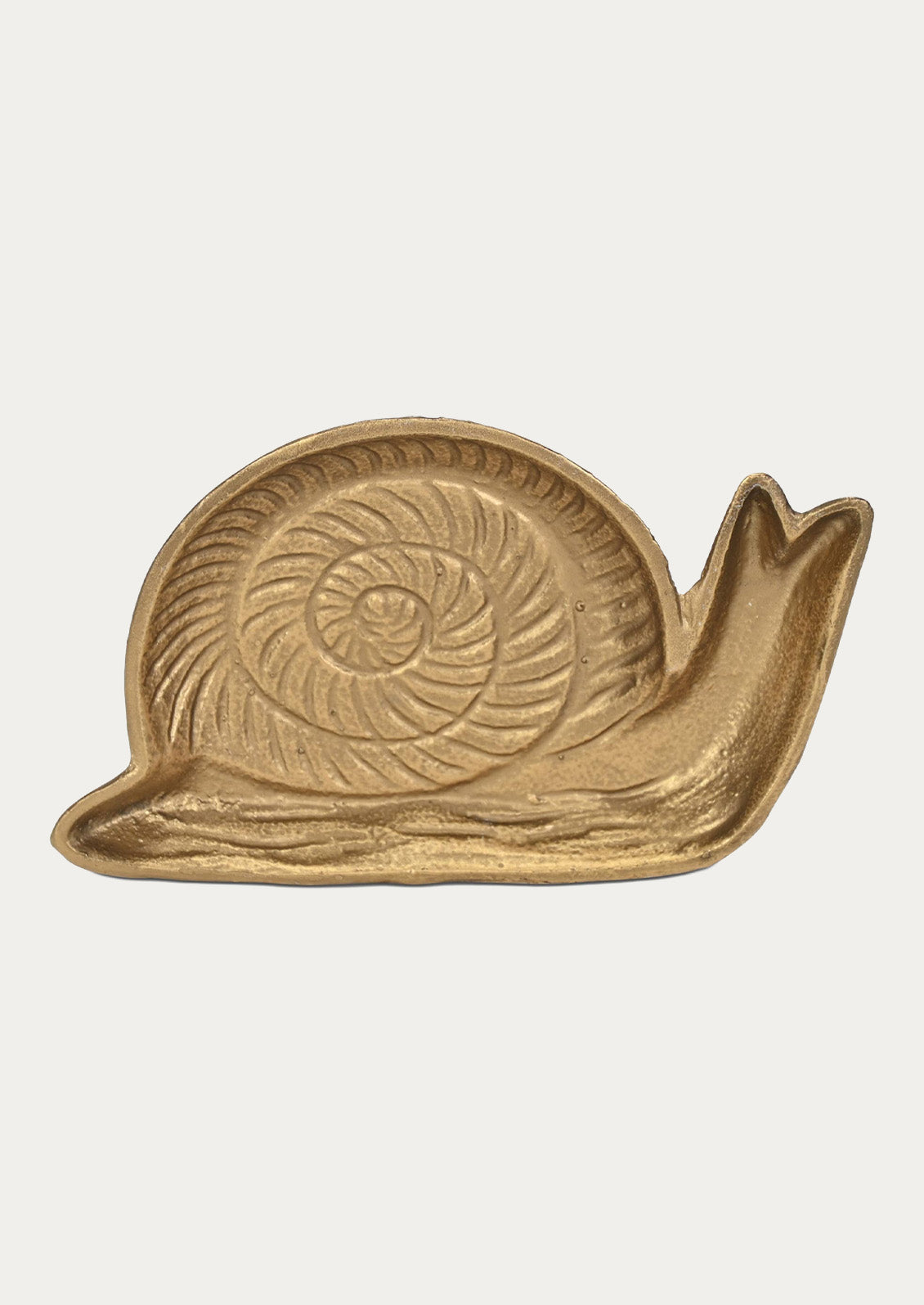 A handcrafted cast iron catchall tray in the shape of s snail in a gold finish on a white background.