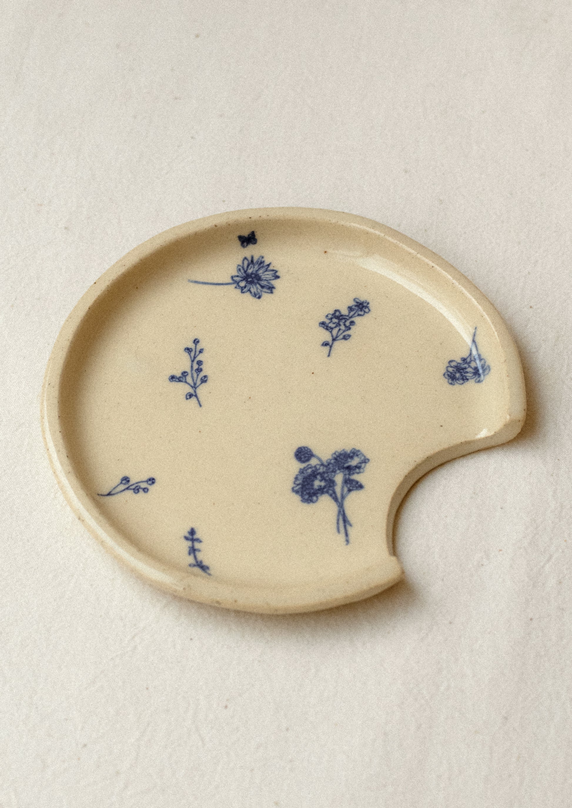 An ivory ceramic spoon rest with delicate blue floral pattern.