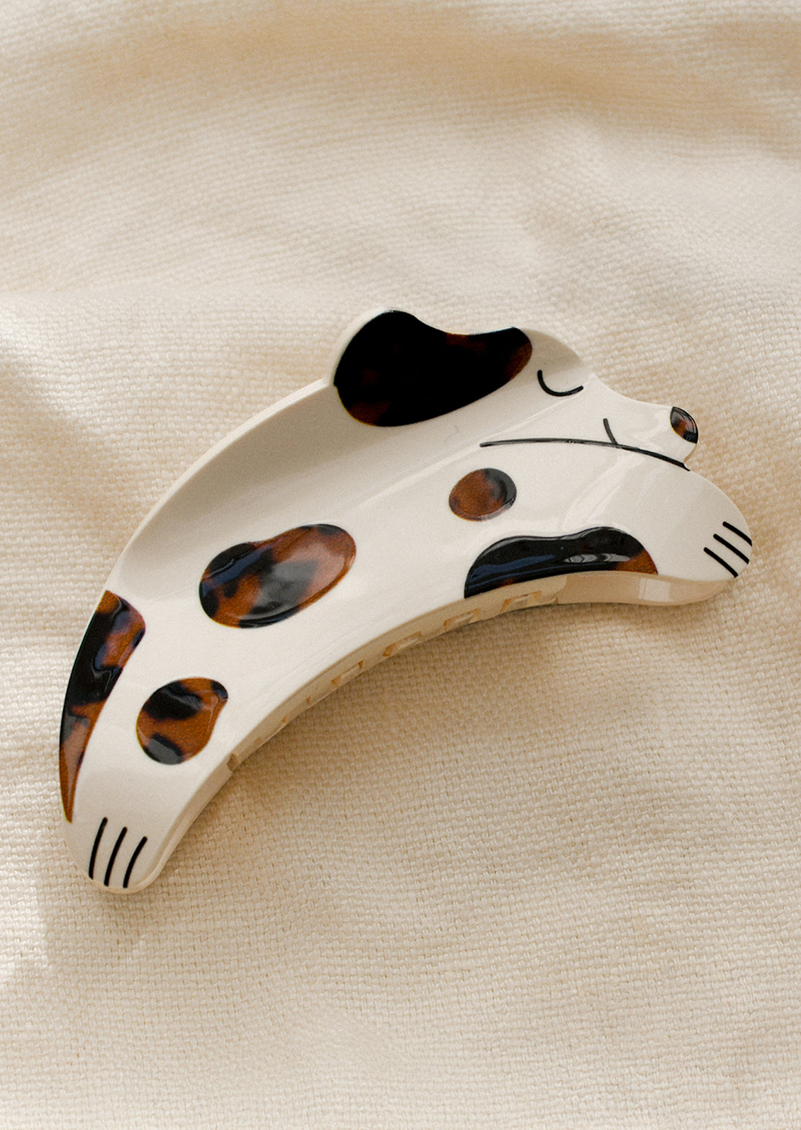 A hair claw in shape of dog, eyes closed with brown tortoise spots.