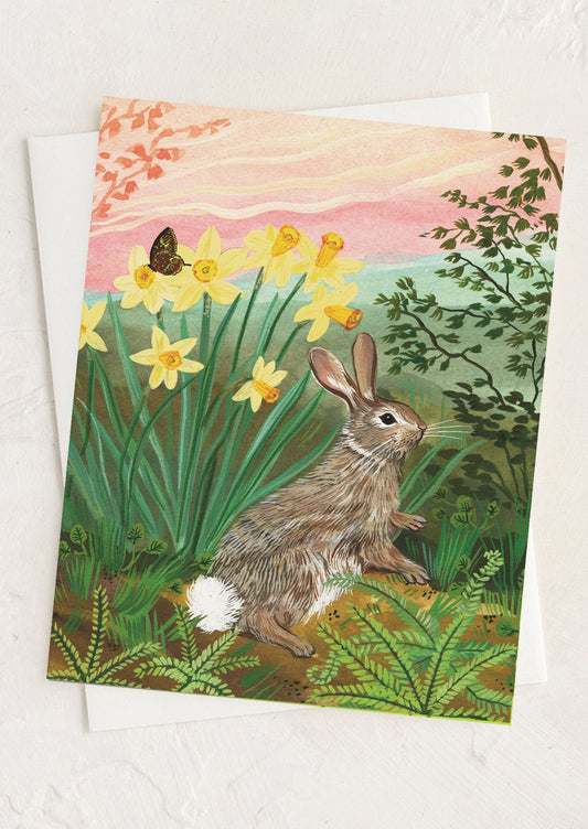 Greeting card with a rabbit and daffodils in a garden setting