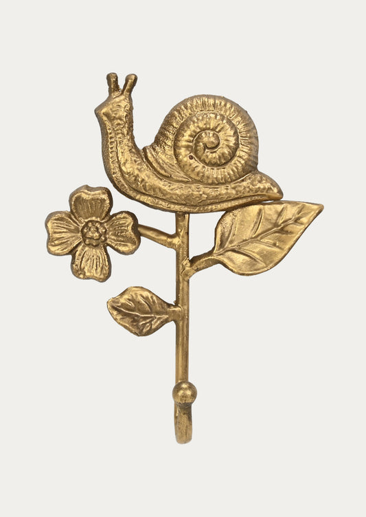 A handcrafted cast iron wall hook in the shape of a snail, flower, and leaves in a gold finish on a white background.