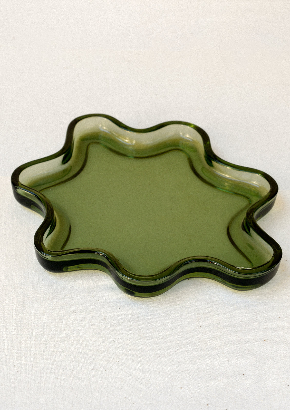 An olive green glass tray in a squiggle shape.