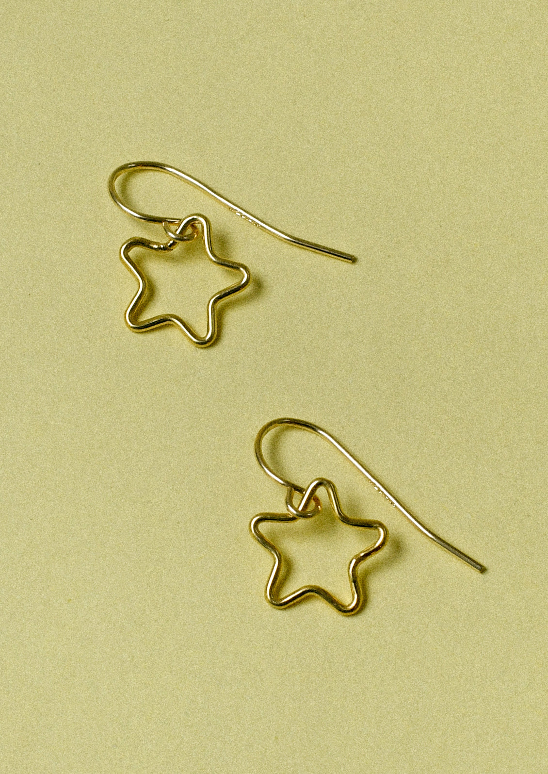 A pair of gold earrings with dangling cut out stars.