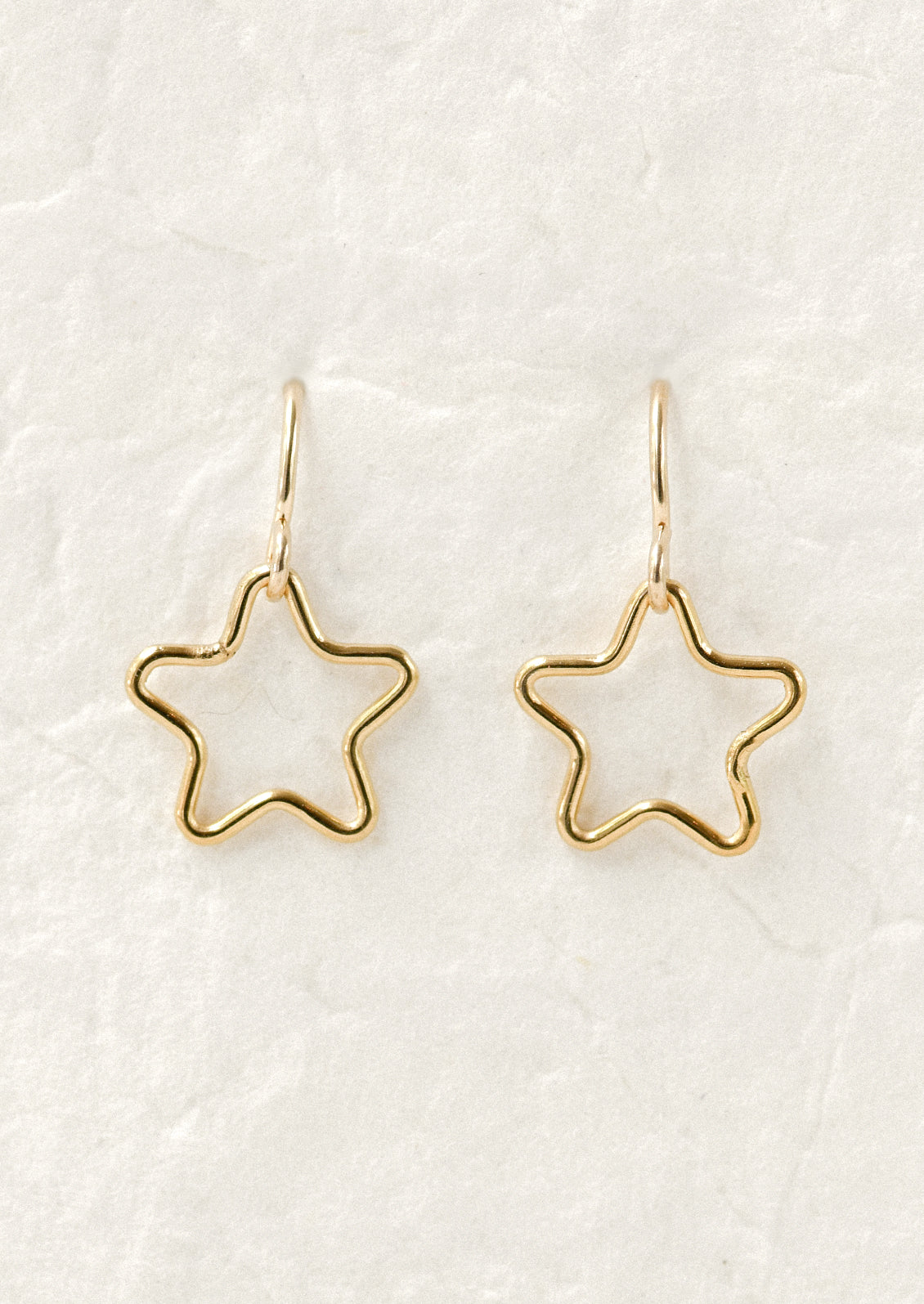 A pair of gold earrings with dangling cut out stars.
