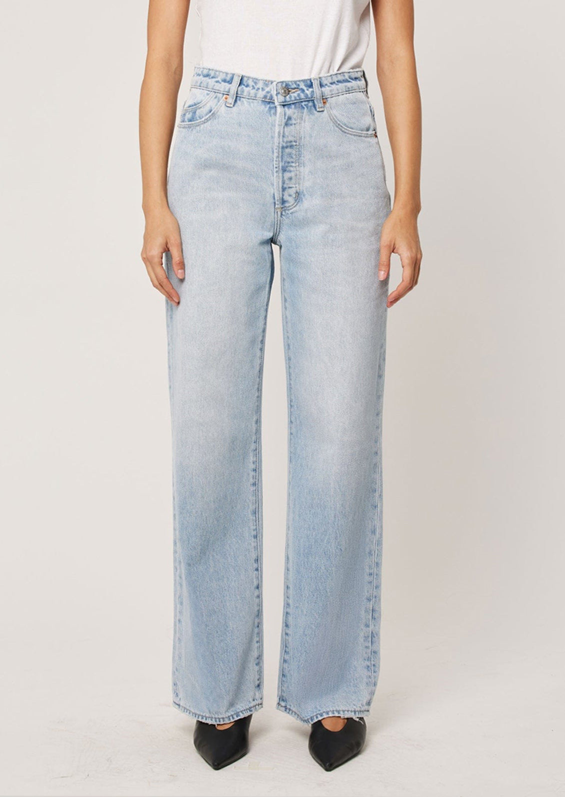 A person wearing a pair of straight leg relaxed jeans in light blue denim.