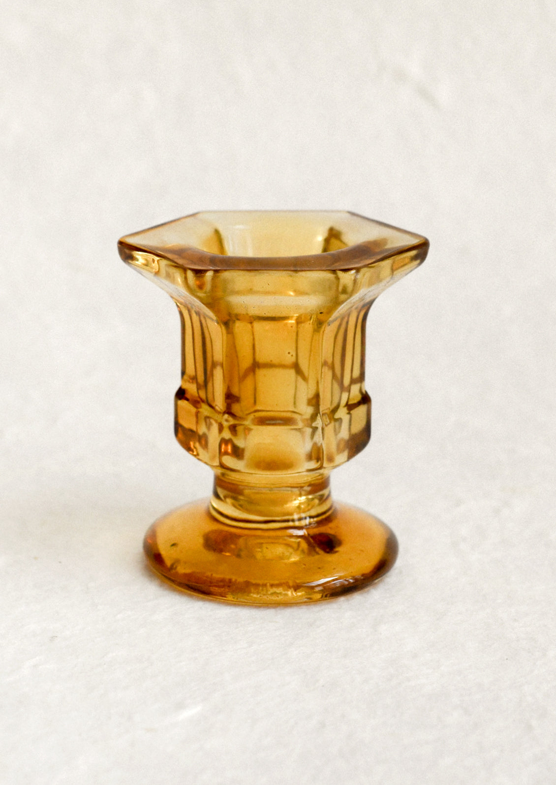 A footed glass candleholder in amber.