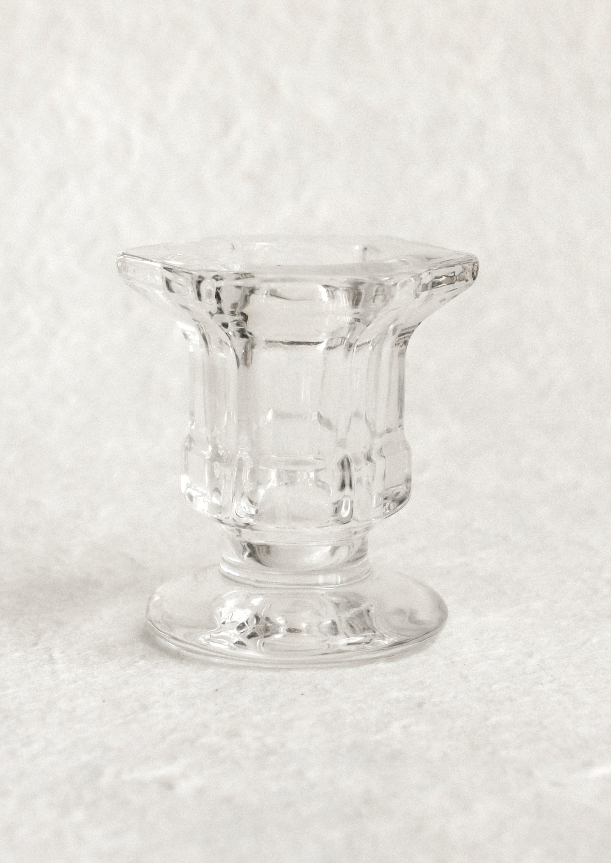 A footed glass candleholder in clear glass.