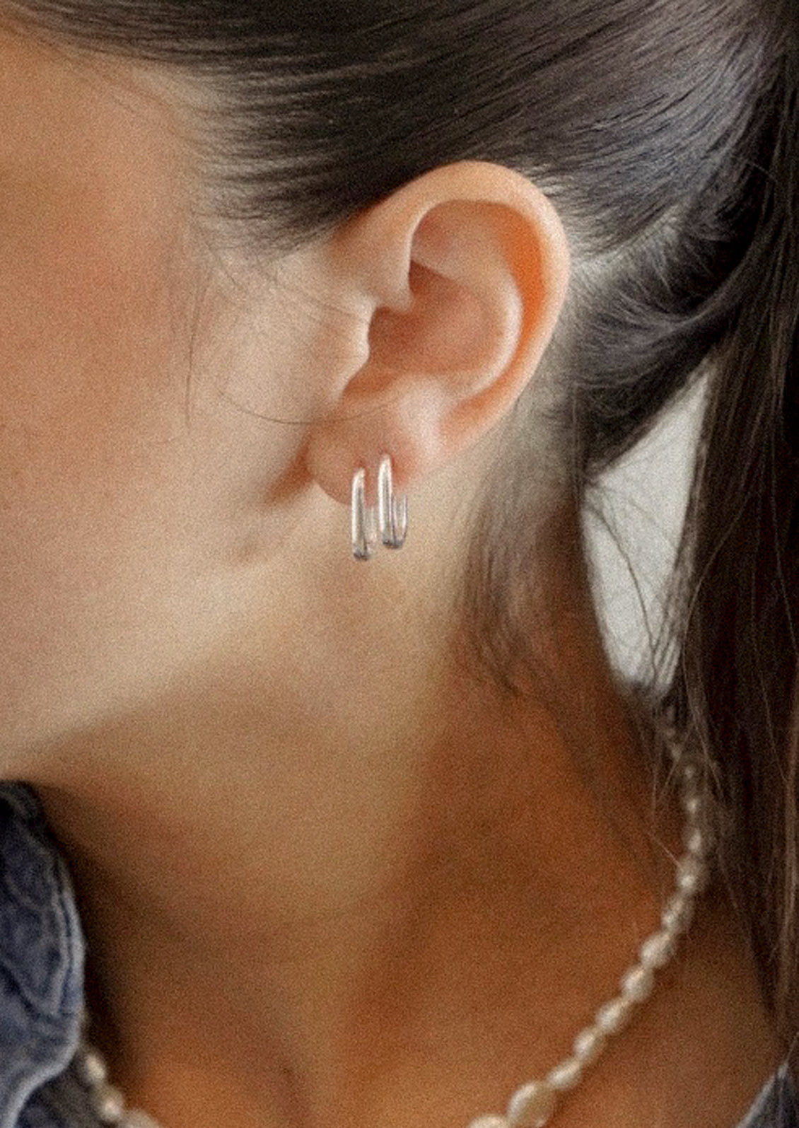 A woman wearing a pair of sterling silver hoop earrings.
