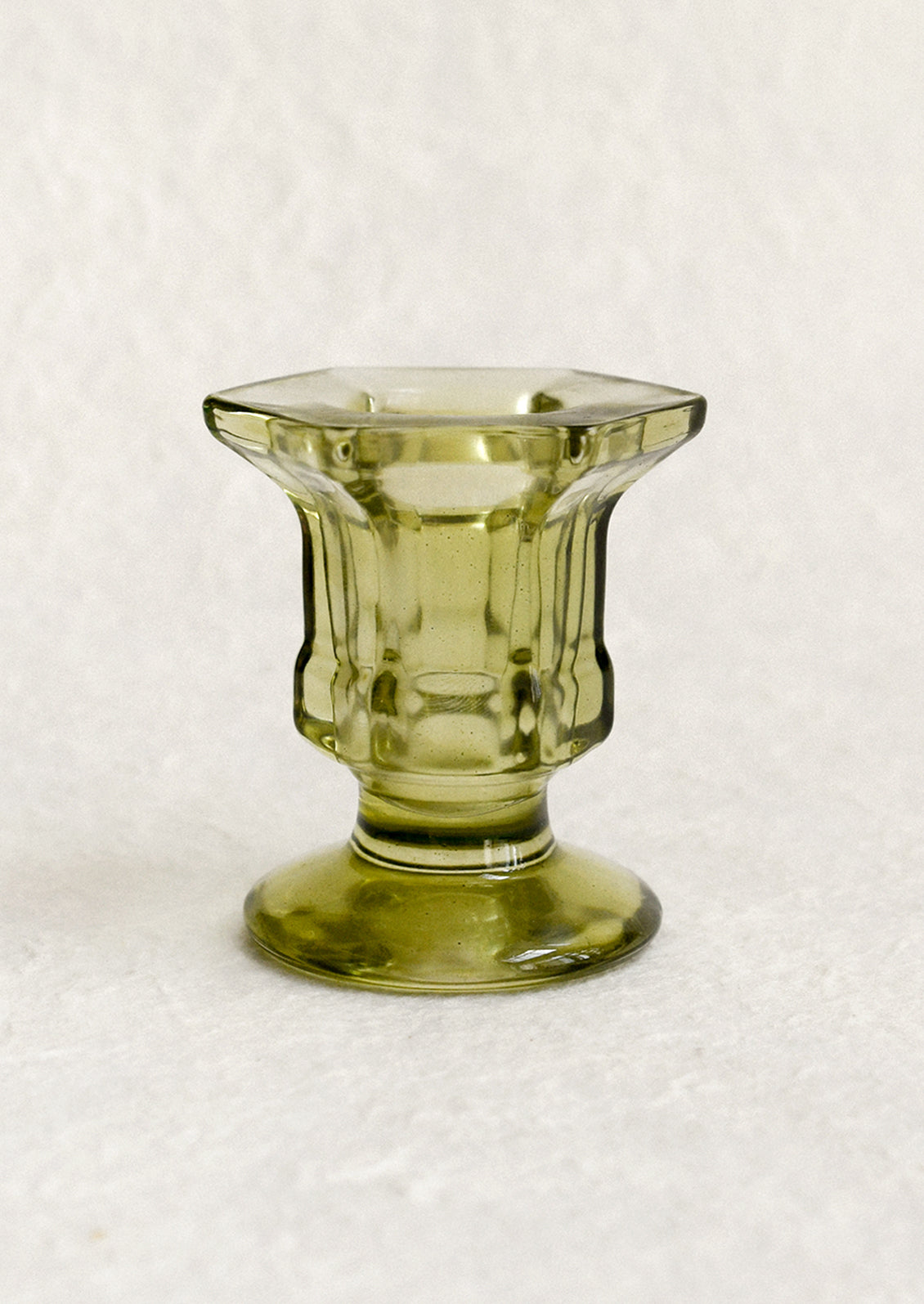 A footed glass candleholder in olive green.