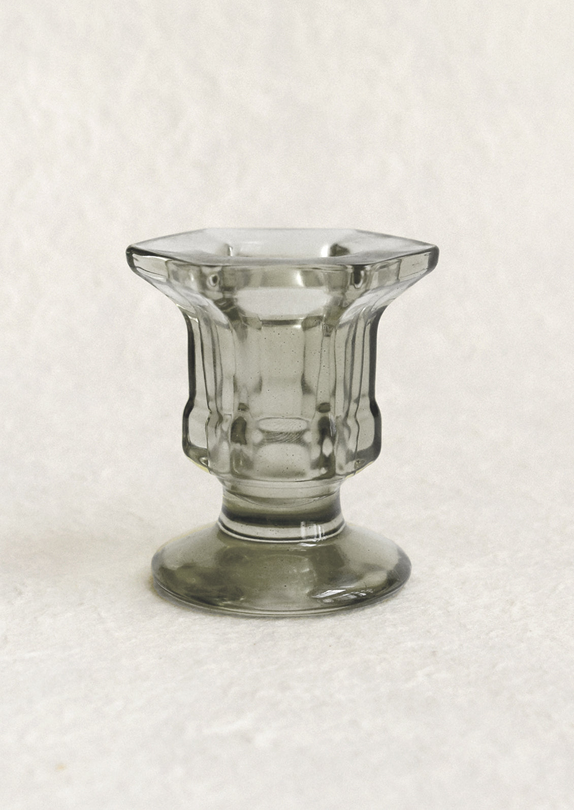 A footed glass candleholder in smoke grey.