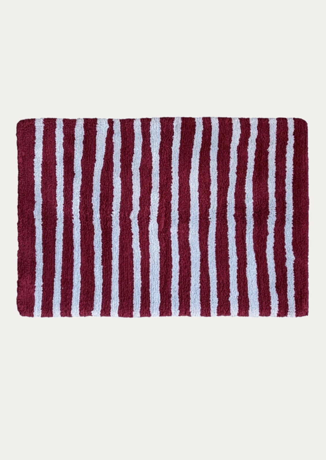 A rectangular bath rug with vertical burgundy and periwinkle stripes, shown flat against a light off-white background.