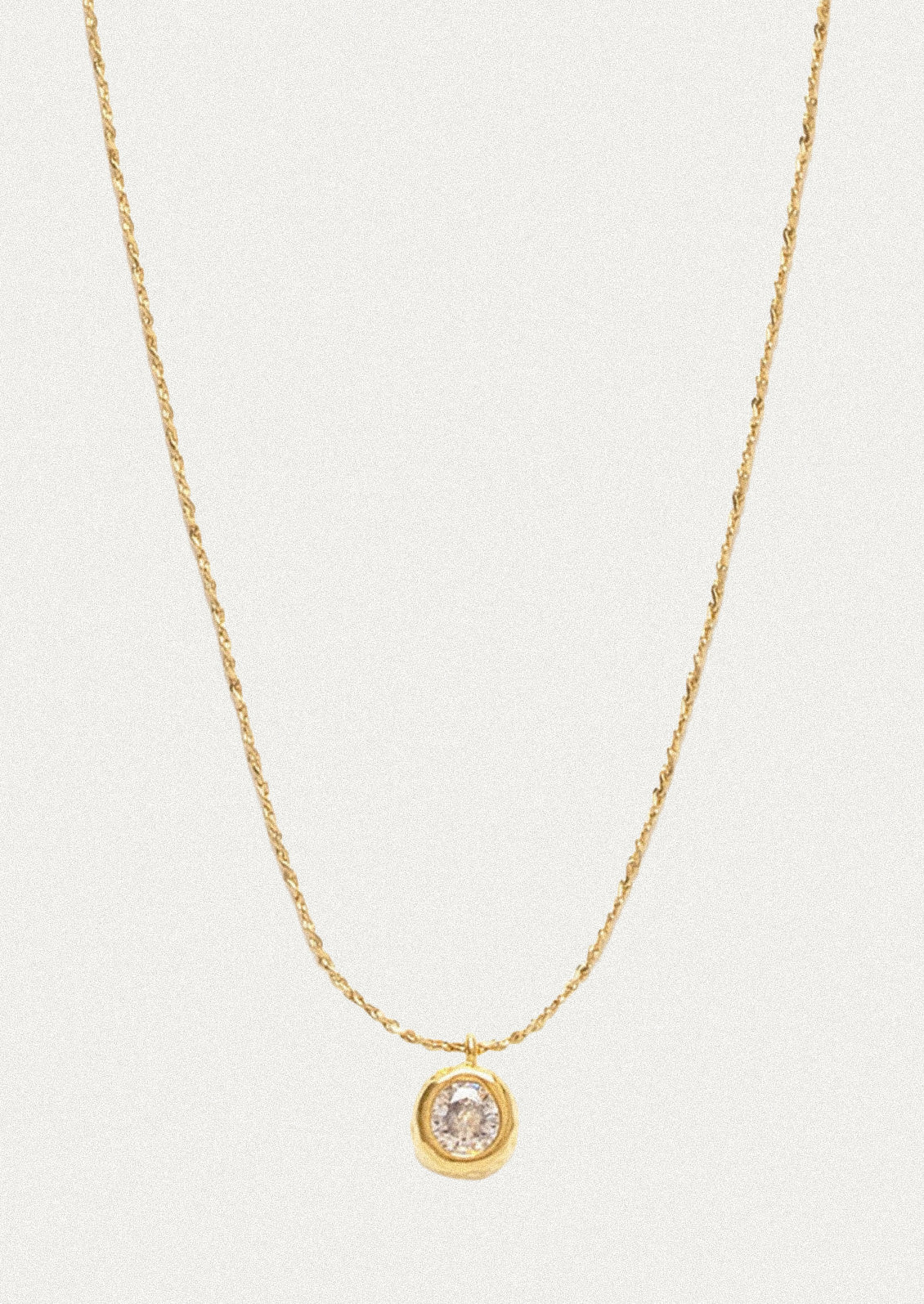 A minimal gold bracelet with a small crystal pendant.