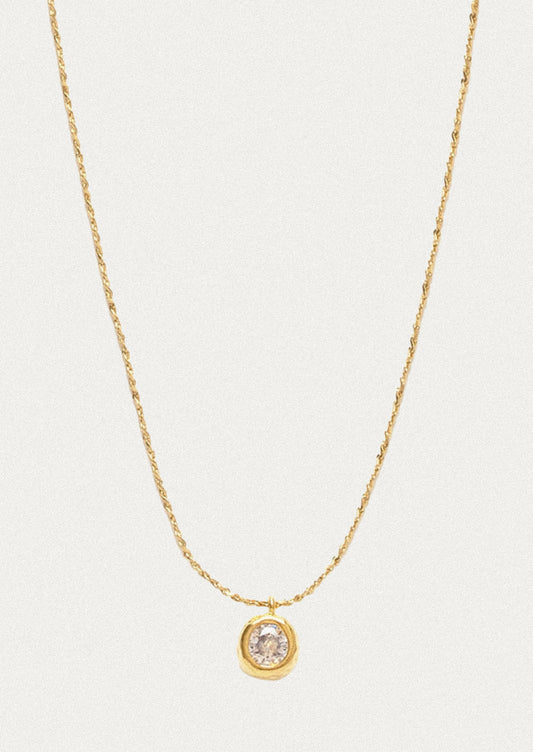 A minimal gold bracelet with a small crystal pendant.