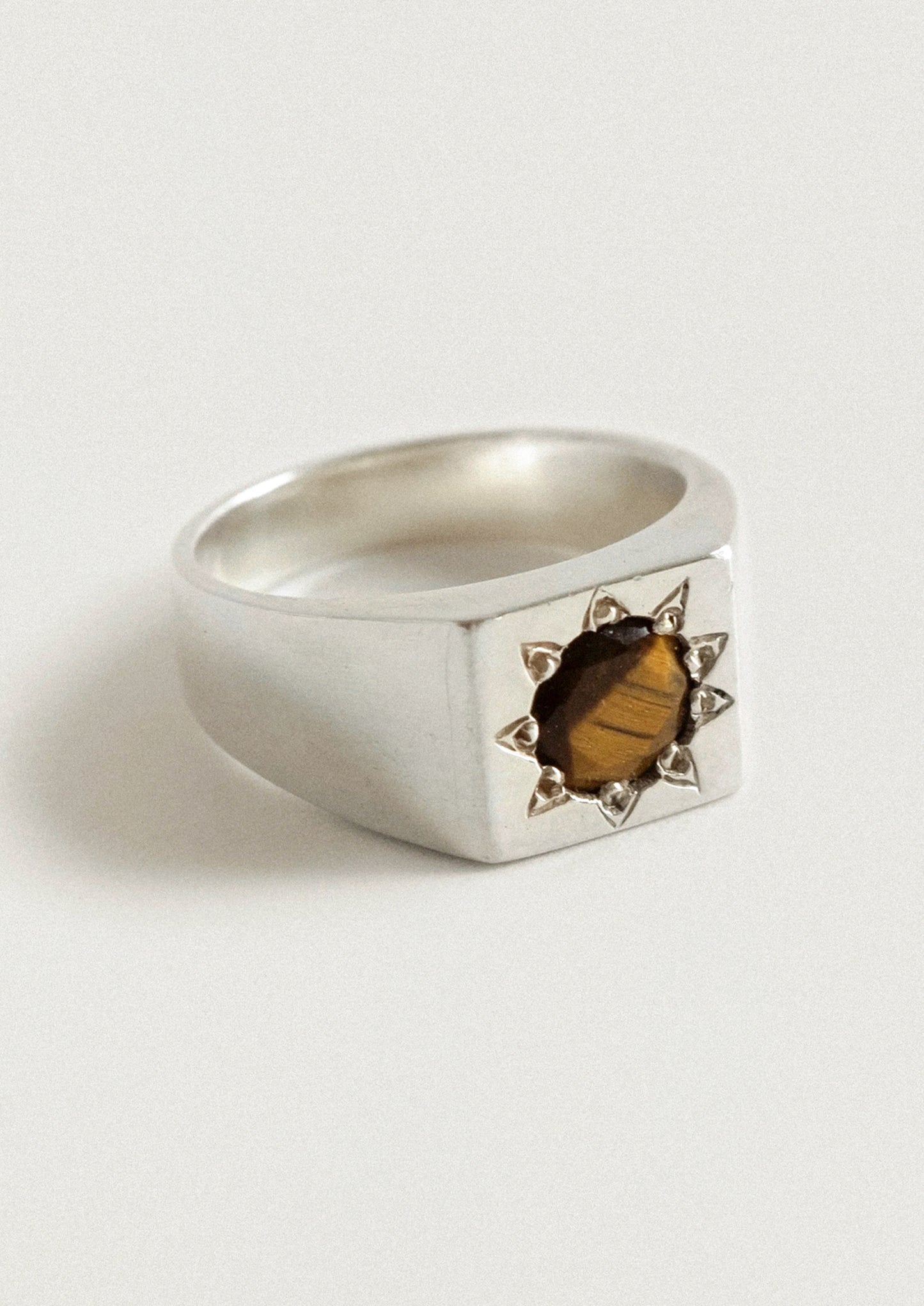A chunky sterling silver ring with a starburst design and a brown gemstone in the center.