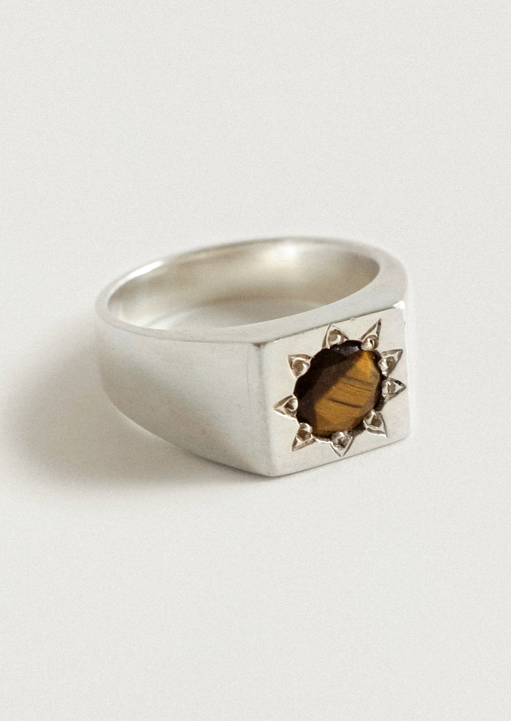 A chunky sterling silver ring with a starburst design and a brown gemstone in the center.