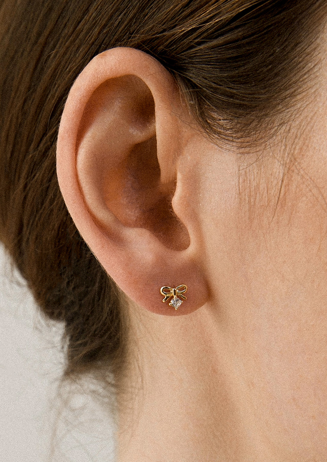 A person wearing a pair of bow shaped studs.