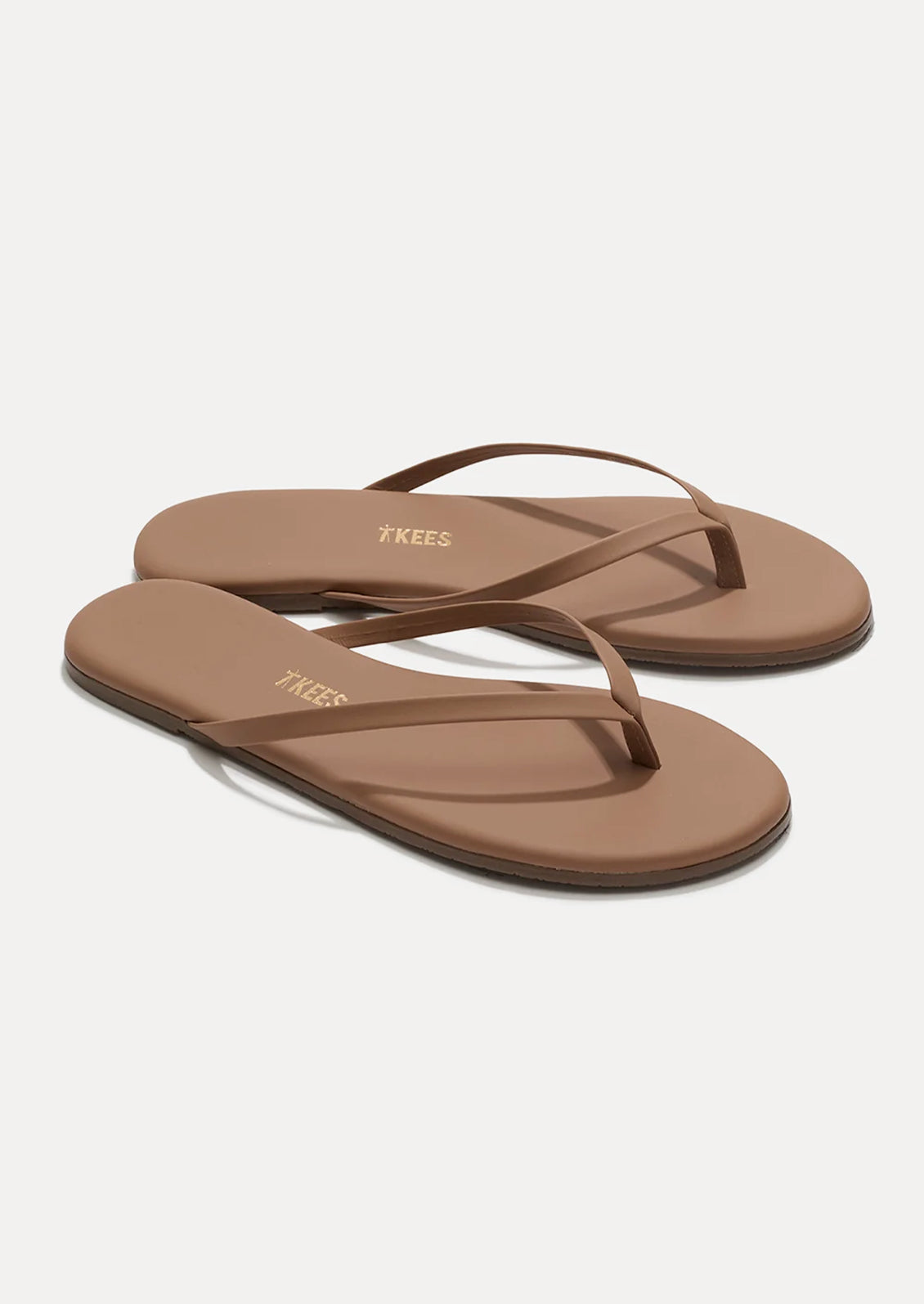 A pair of leather skinny strap TKEES sandals in nude.