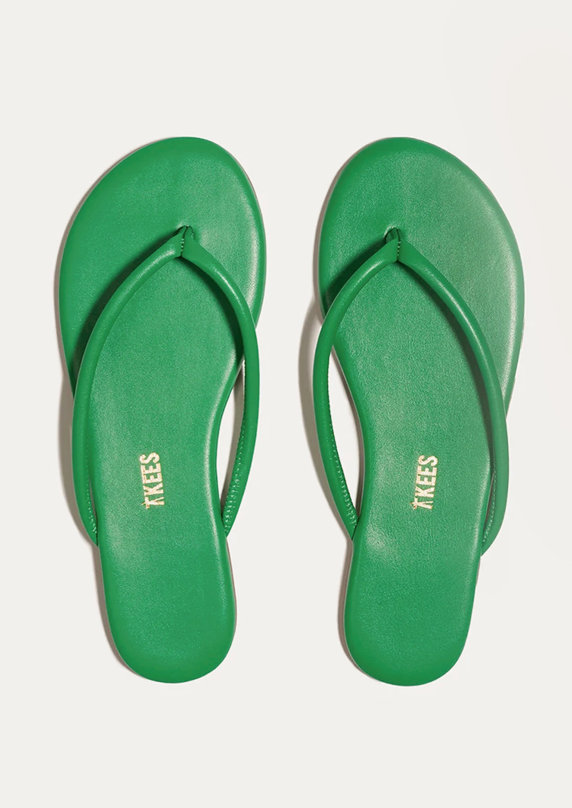 A pair of leather TKEES sandals with a tubular strap design in kelly green.
