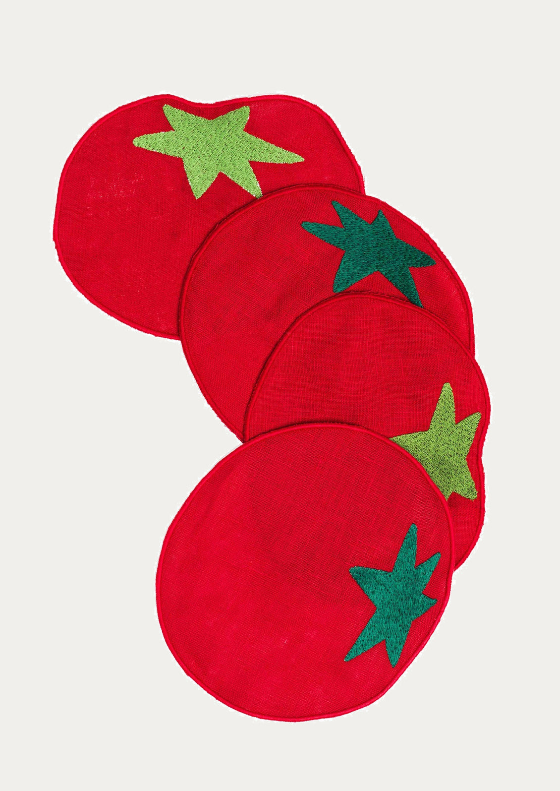Red tomato coasters with green leaf designs on a white background