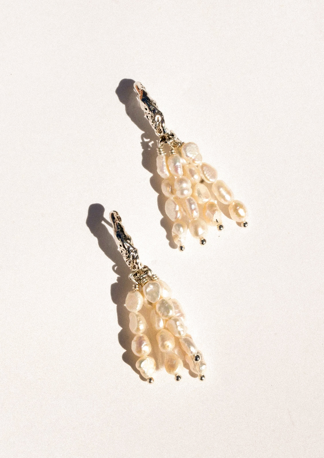 A pear of sterling silver earrings featuring dangling pearl clusters.
