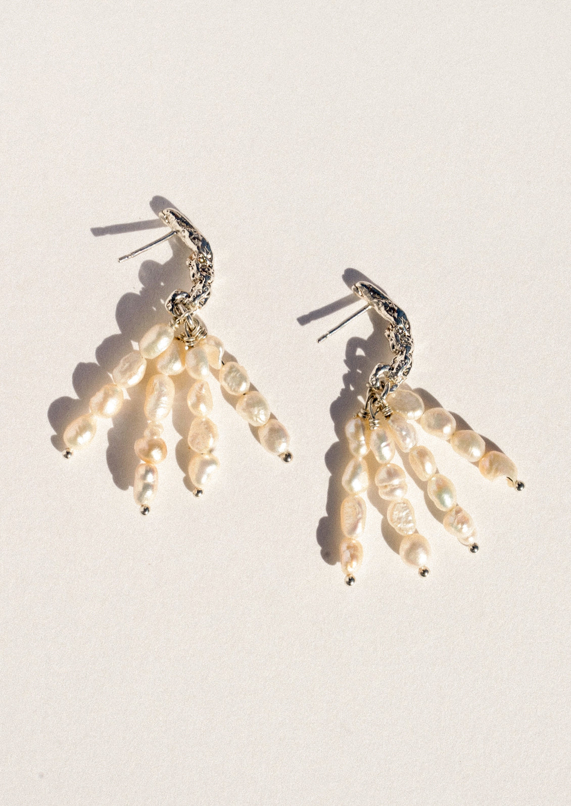 A pear of sterling silver earrings featuring dangling pearl clusters.