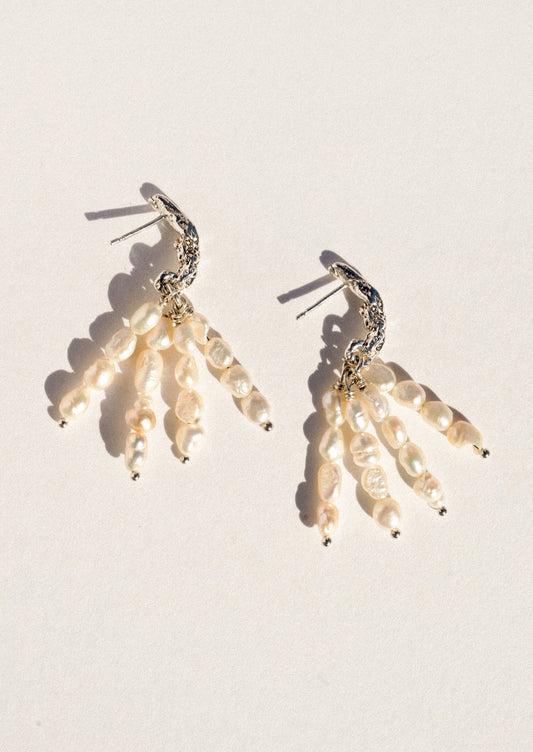 A pear of sterling silver earrings featuring dangling pearl clusters.