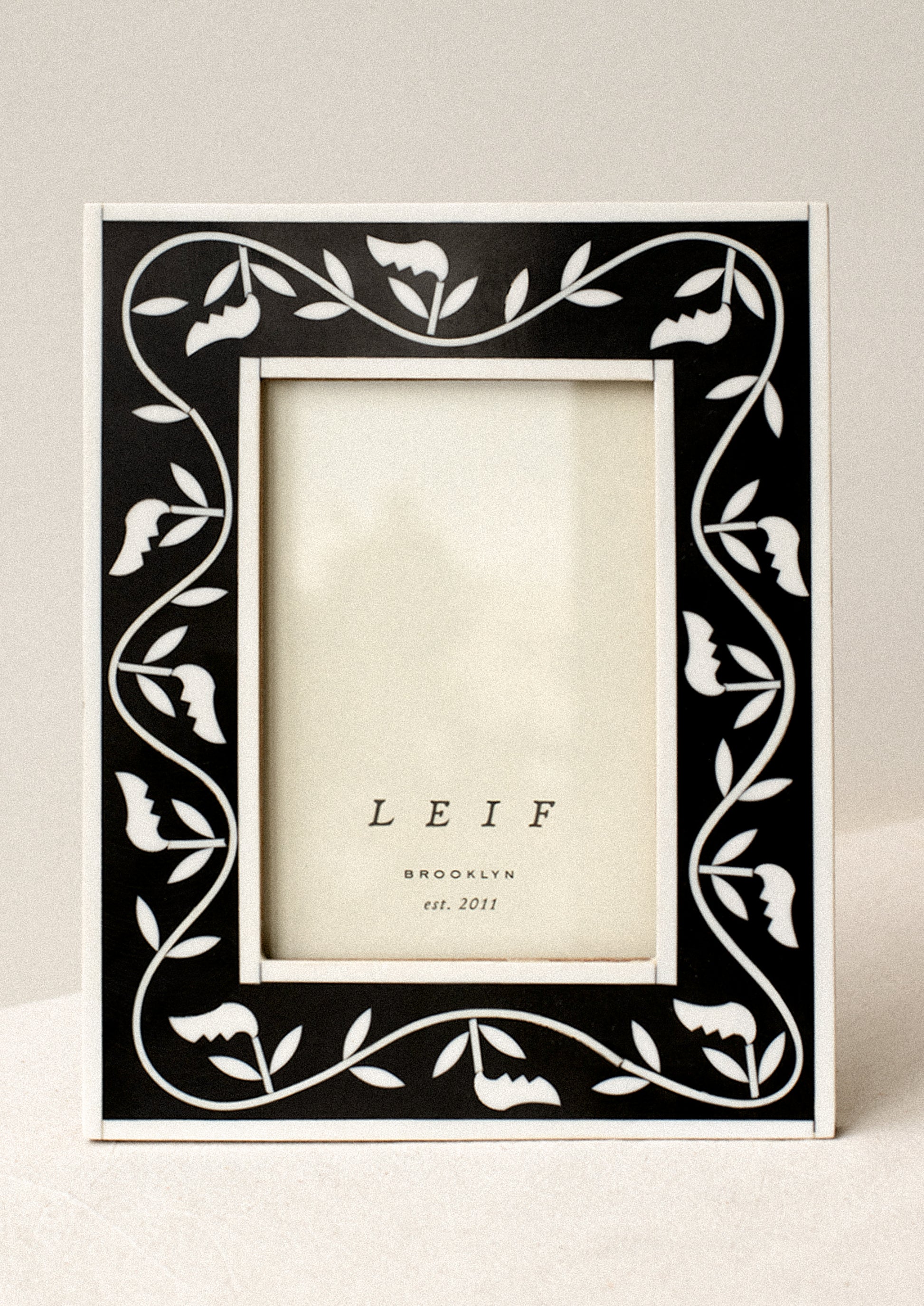 A black and white inlay frame with leaf pattern.