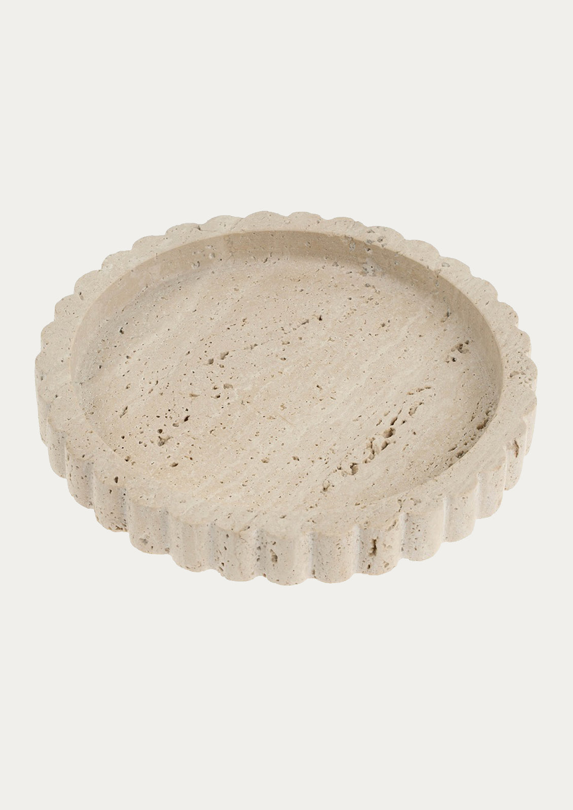 A round shaped travertine tray with scalloped edges.