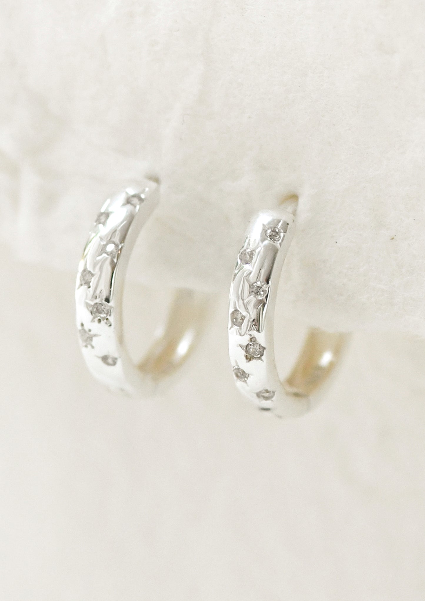 A pair of sterling silver hoop earrings with star gems.