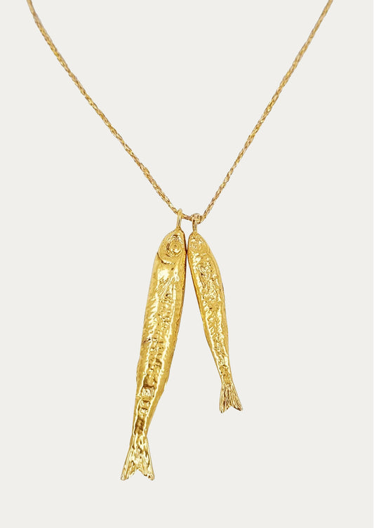 A necklace on gold string with two fish charms.